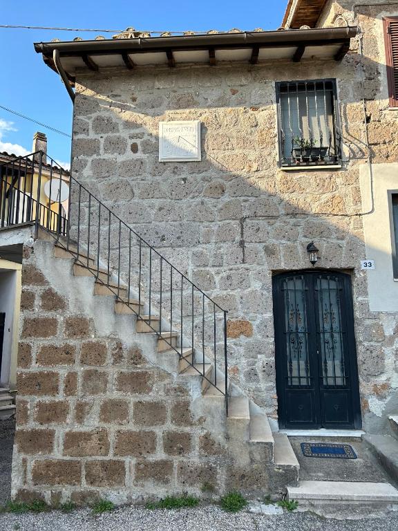 a stone building with a black door and stairs at La Meridiana in Faleria