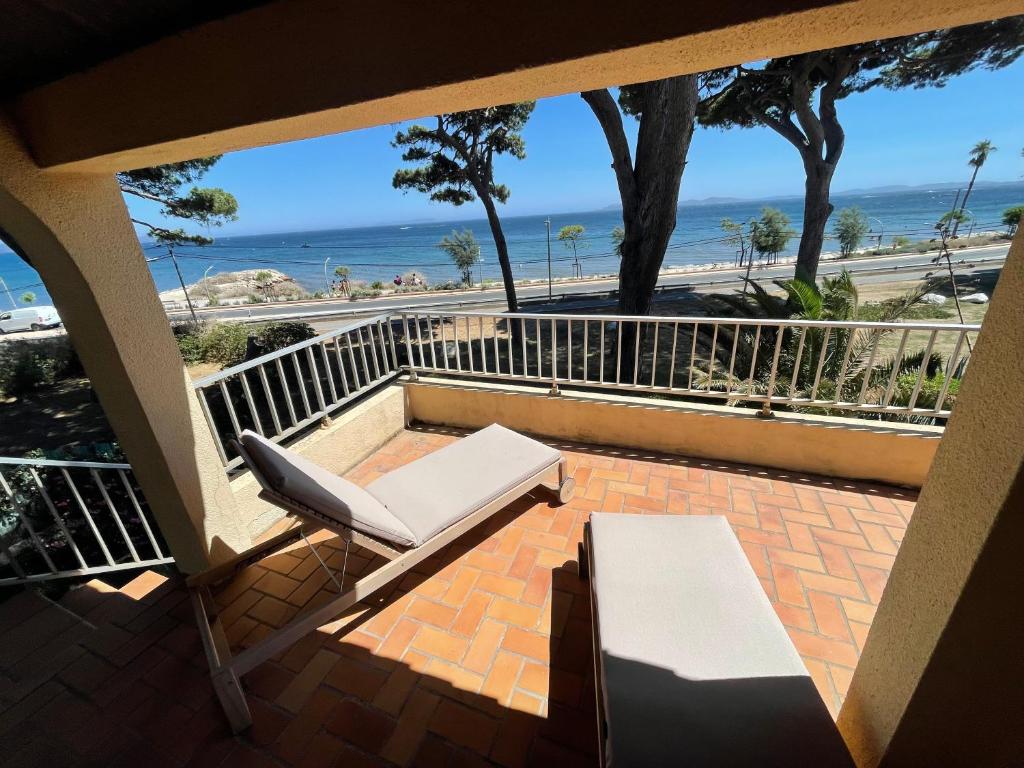 - un balcon avec une chaise et un banc donnant sur l'océan dans l'établissement Au bord de mer à Hyères les Palmiers, à Hyères