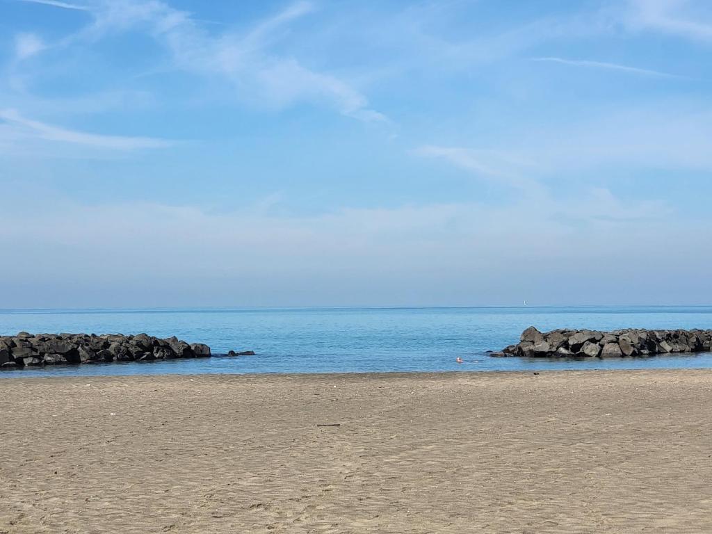 a beach with rocks in the water and a blue sky at Leonardo Da Vinci Guest House in Fiumicino
