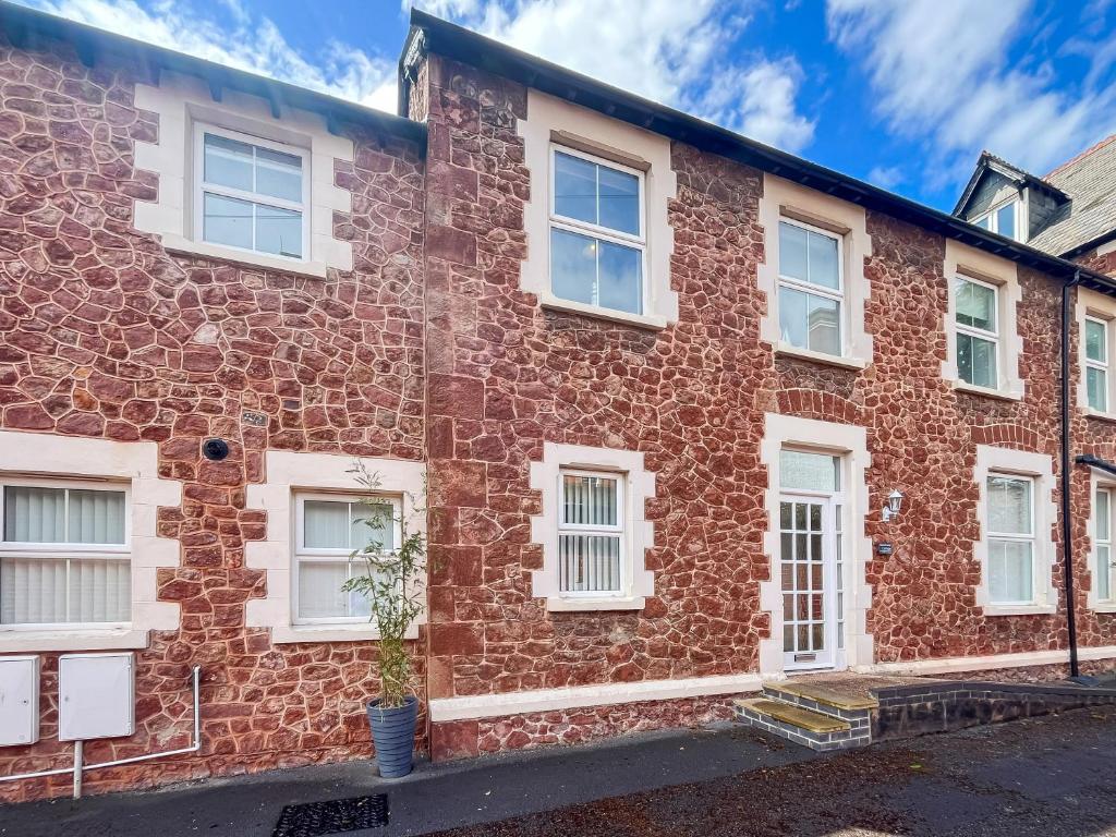 a brick building with white windows on a street at Beachside Cottage Minehead in Minehead