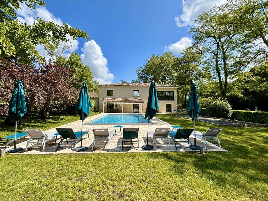 a yard with chairs and umbrellas and a pool at La Maison L'Eperon, stylish 5 star villa surrounded by vineyard near Saint Emilion in Vérac