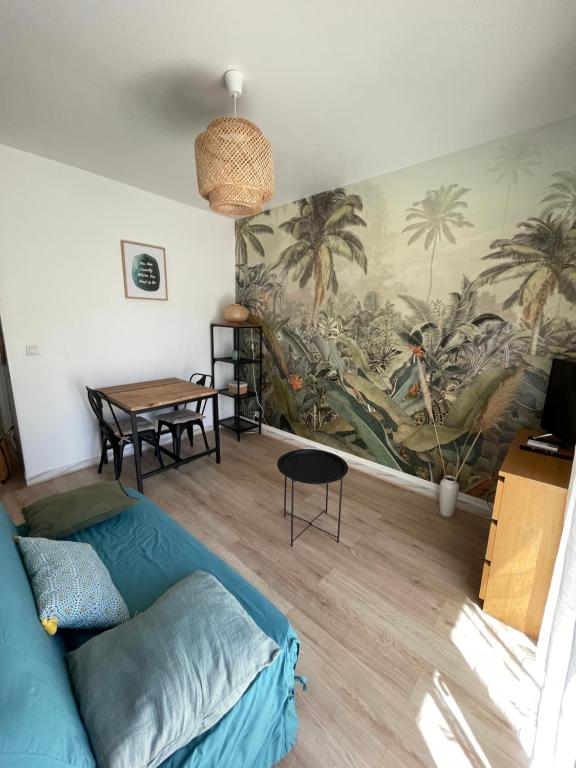 - un salon avec un canapé bleu et une fresque murale dans l'établissement Studio climatisé avec balcon à 10 mn des plages, à Saint-Raphaël