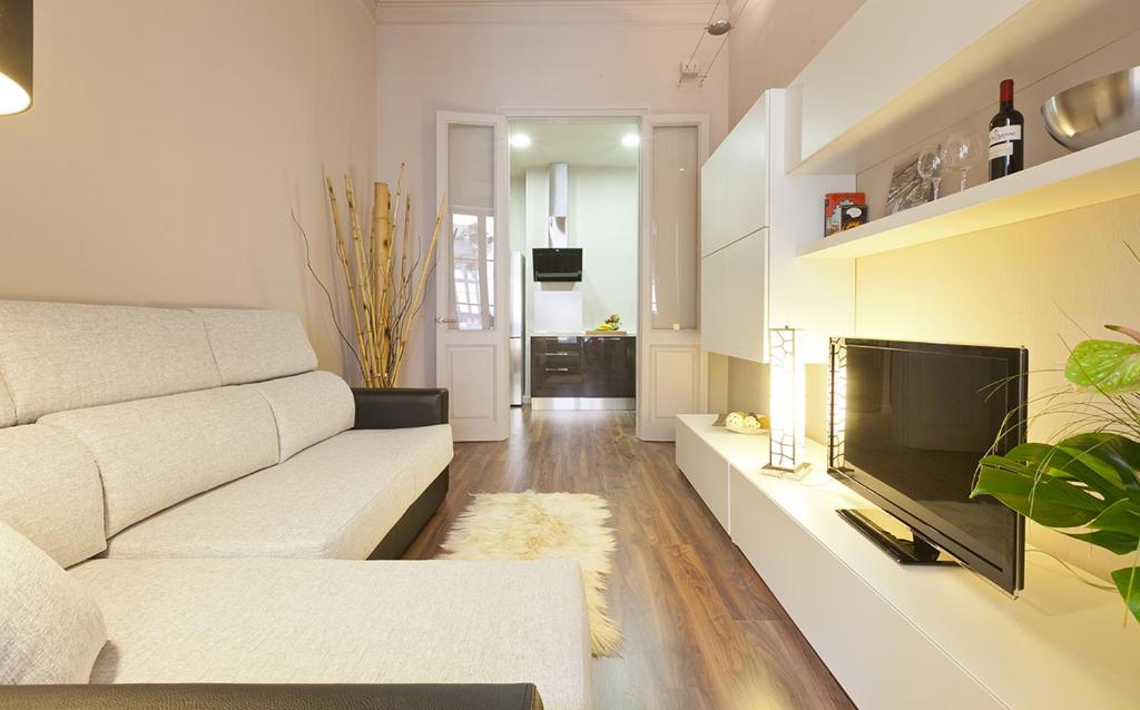 a living room with a white couch and a flat screen tv at Eixample patio views with amazing terrace in Barcelona