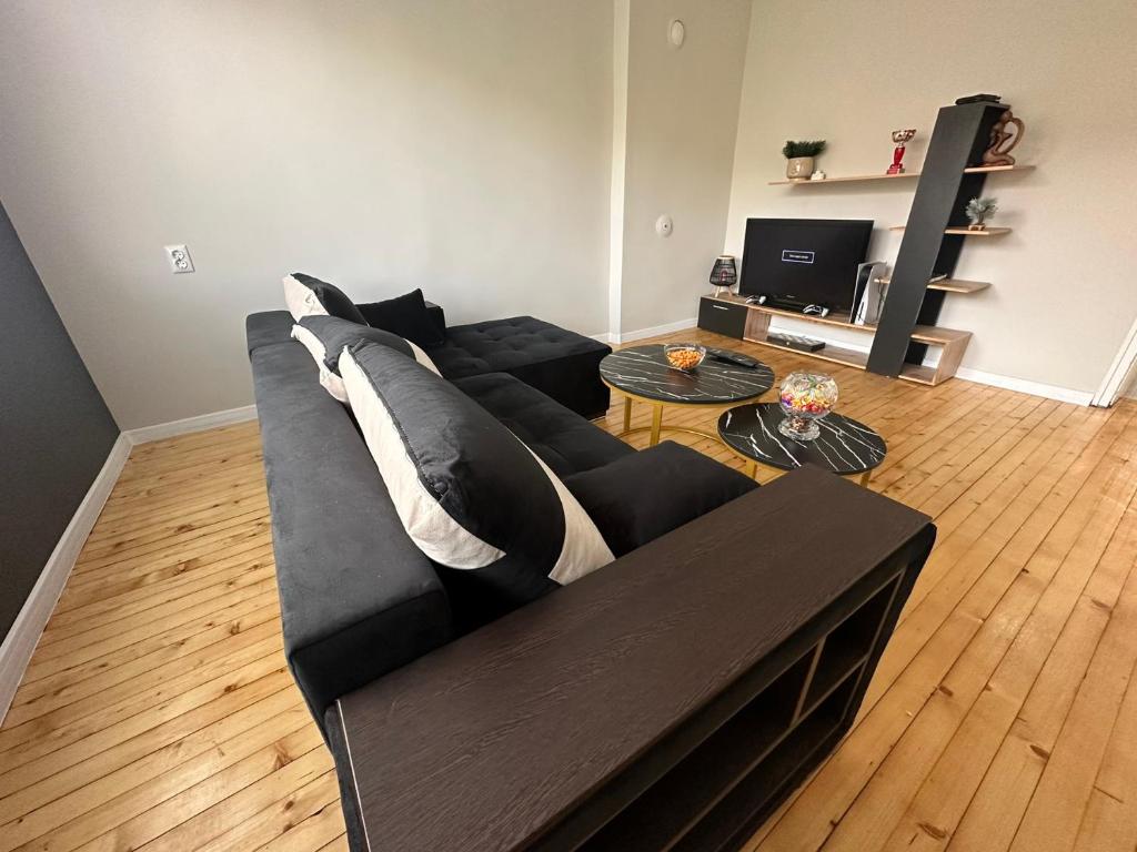 a living room with a black couch and a table at Calipsso Apartment's in Belogradchik