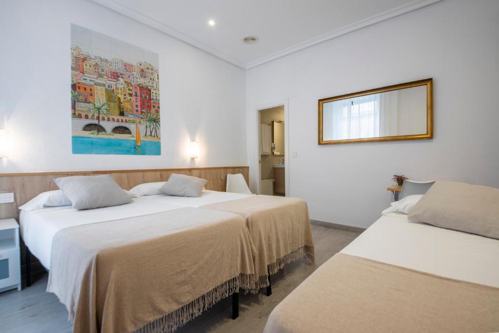 Una habitación con dos camas y un cuadro en la pared. en Pensión Donostiarra, en San Sebastián