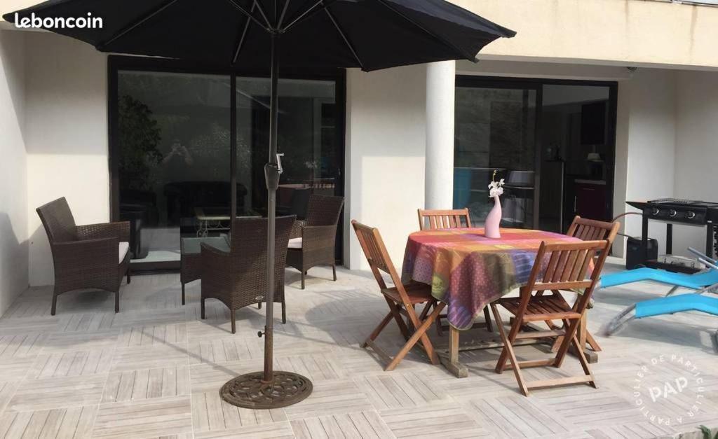 une table et des chaises avec un parasol sur une terrasse dans l'établissement Location Appartement Sainte-Maxime 7 personnes, à Sainte-Maxime