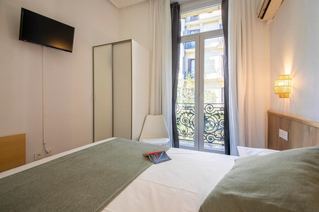 Un dormitorio con una cama y una ventana grande. en Pensión Donostiarra, en San Sebastián
