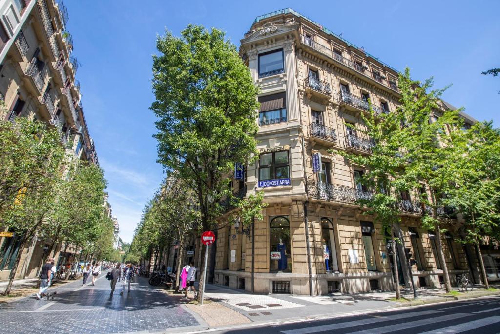 un edificio alto en una calle con gente caminando delante de él en Pensión Donostiarra, en San Sebastián