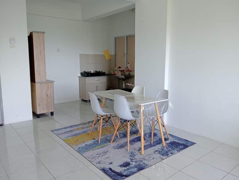 a kitchen with a table and chairs on a rug at EM Camar Seaview Homestay at Sutra Villa2 in Kuantan