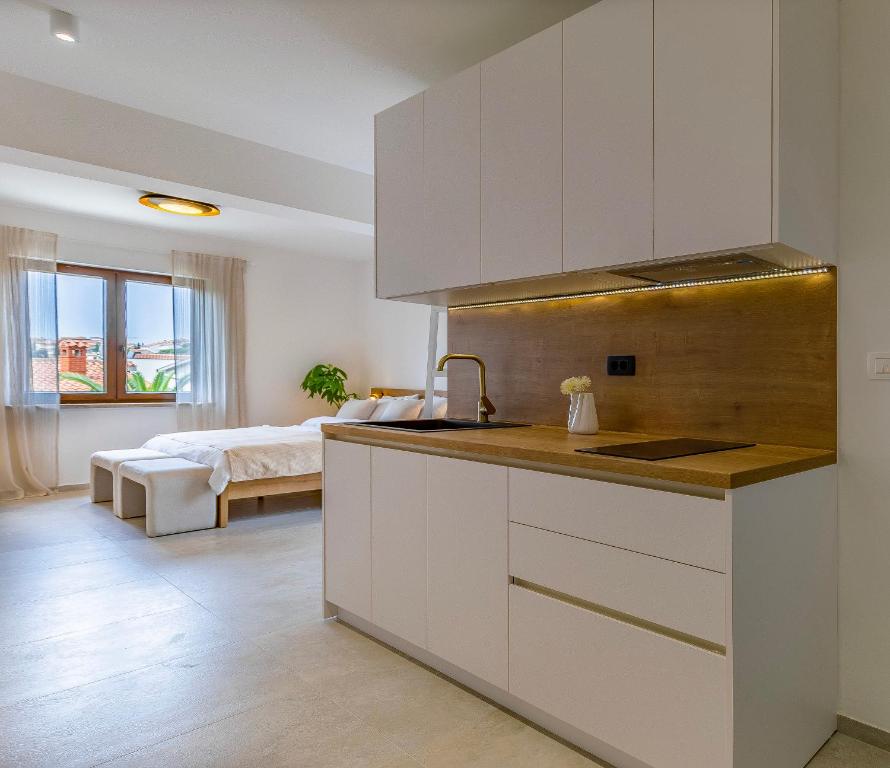 a kitchen with white cabinets and a bed in the background at Studio Percan in Premantura