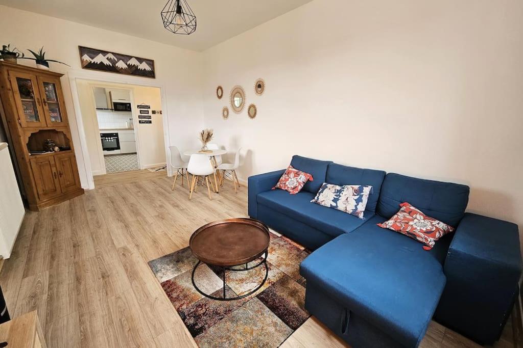 un salon avec un canapé bleu et une table dans l'établissement Logement 68 m2 confortable et cosy - Corrèze, à Saint-Privat