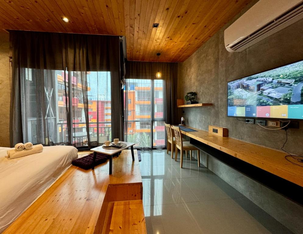 a hotel room with a bed and a desk and a tv at Mira Naiharn, Minimalist Design & Mountain View at Relife Windy in Rawai Beach