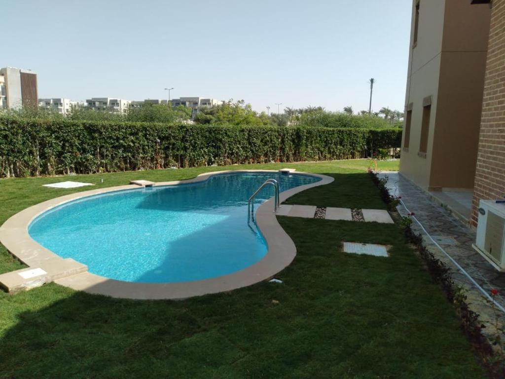 a swimming pool in a yard next to a building at Villa Marassi in El Alamein