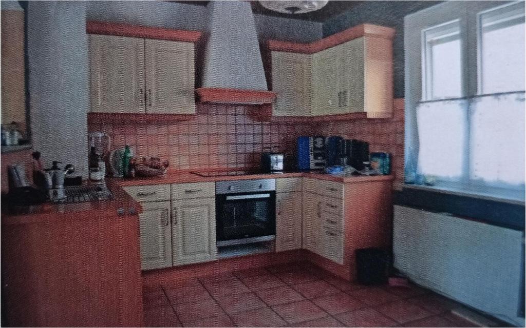 a kitchen with white cabinets and a red tiled floor at Ferienhaus zur Moselfähre in Kröv