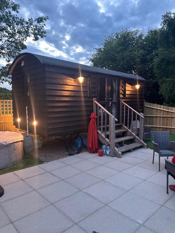 a large wooden shed with a staircase next to a patio at A Snuggles hut in Faversham