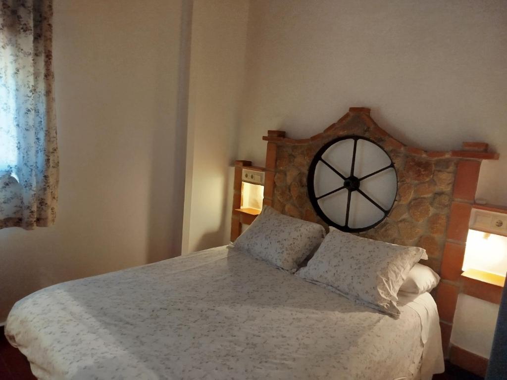 1 dormitorio con 1 cama con reloj grande en la pared en CASA RURAL "LA CASITA" para 2 personas, en Ronda