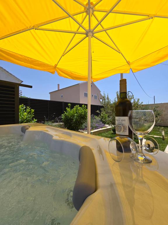 a yellow umbrella and a glass of wine on a table at Luxury Apartment Gašpa with jacuzzi in Privlaka
