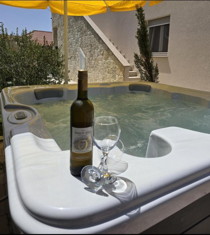 a bottle of wine and a wine glass on a table in a swimming pool at Luxury Apartment Gašpa with jacuzzi in Privlaka