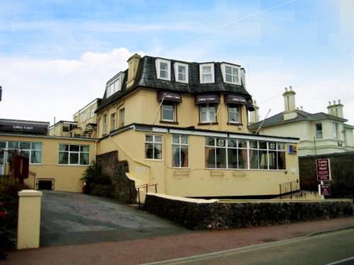 a large yellow building with a black roof at Ashley Court Hotel in Torquay