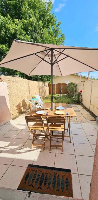 - une table en bois avec un parasol sur la terrasse dans l'établissement La CAMPA CAZALINE, à La Teste-de-Buch