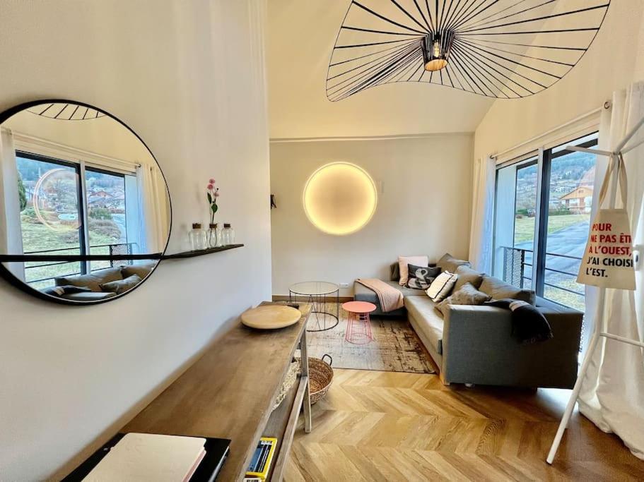 un salon avec un canapé et un grand miroir dans l'établissement Les deux maisons - Le 68 - Appartement et balcon vue pistes proche lac, à Gérardmer