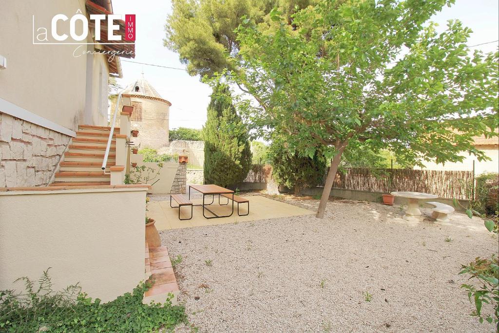 une cour avec un arbre, une table et des escaliers dans l'établissement Le moulin Haut - 8 couchages, à Martigues