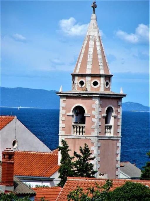 a clock tower with a steeple on top of a building at Vila Klara room - garden view in Olib