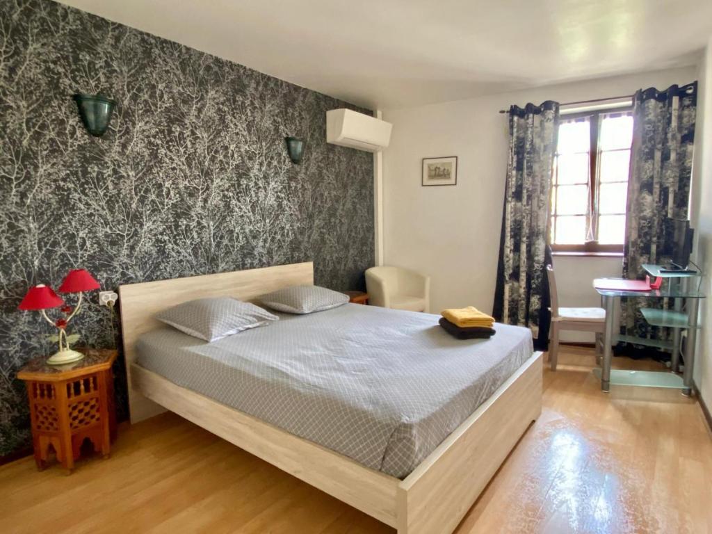 une chambre avec un lit et un mur avec du papier peint à fleurs dans l'établissement Appartement Cité de Carcassonne, à Carcassonne