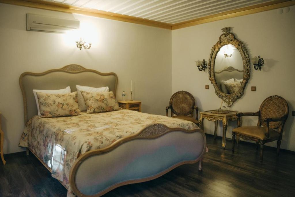 a bedroom with a bed and a mirror and chairs at Konak Macha Boutique & Lounge Otel in Edremit