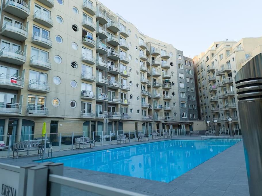 an apartment building with a swimming pool in front of it at Cozy studio with pool close to the sea in Ostend