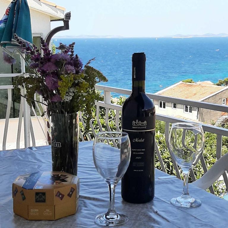 a bottle of wine sitting on a table with two glasses at Apartman Mare BP in Dolac