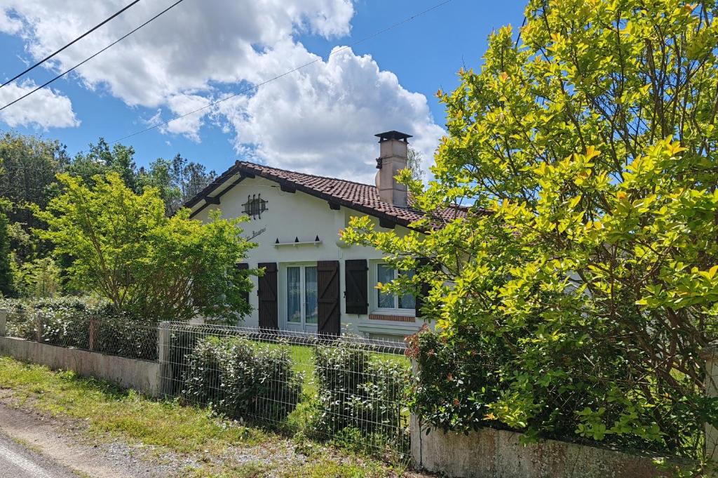 a white house with a chimney and a fence at Les Bruyères - Maison in Léon