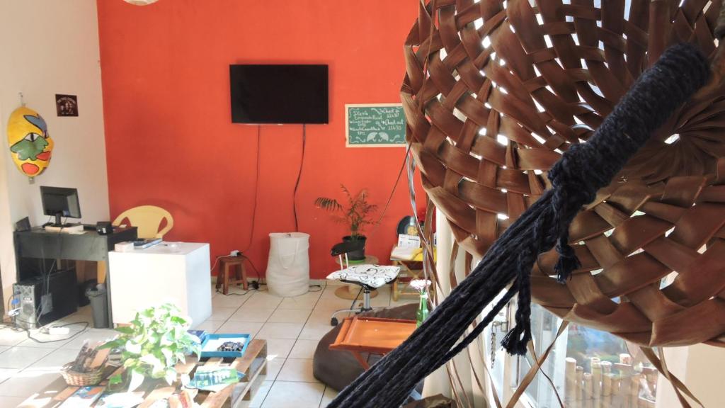 a living room with a red wall and a tv at Ramon Hostel Bar in Recife