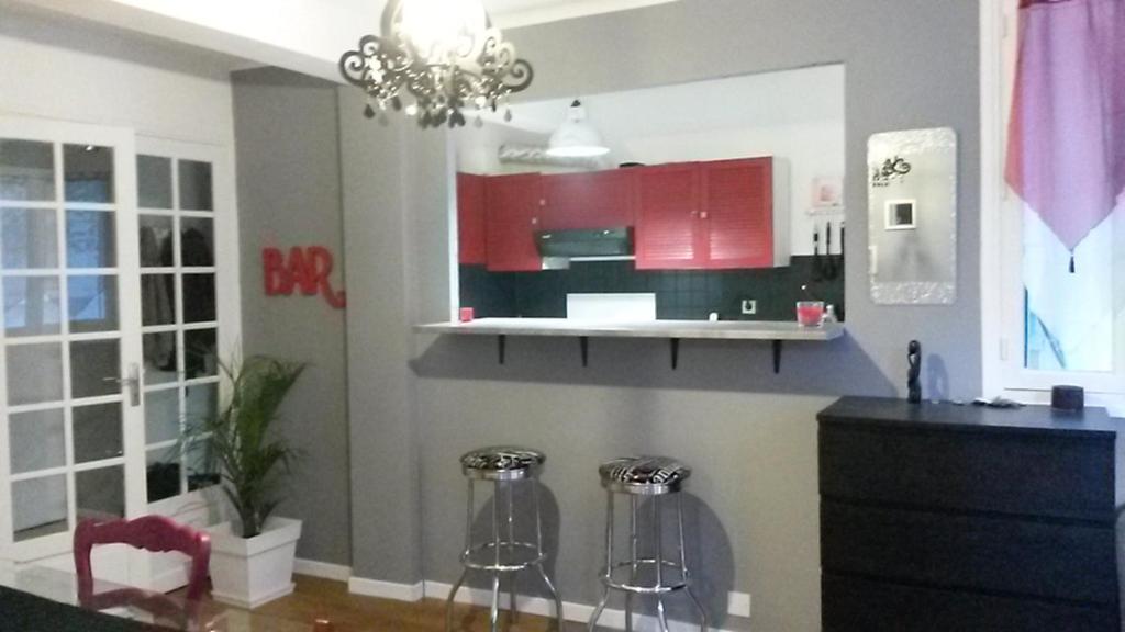 une cuisine avec des placards rouges et deux tabourets de bar dans l'établissement Bel appartement T2 bis à deux pas de l'hypercentre, à Toulouse