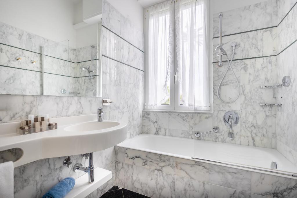 a white bathroom with a tub and a sink at Hotel Metropole in Santa Margherita Ligure