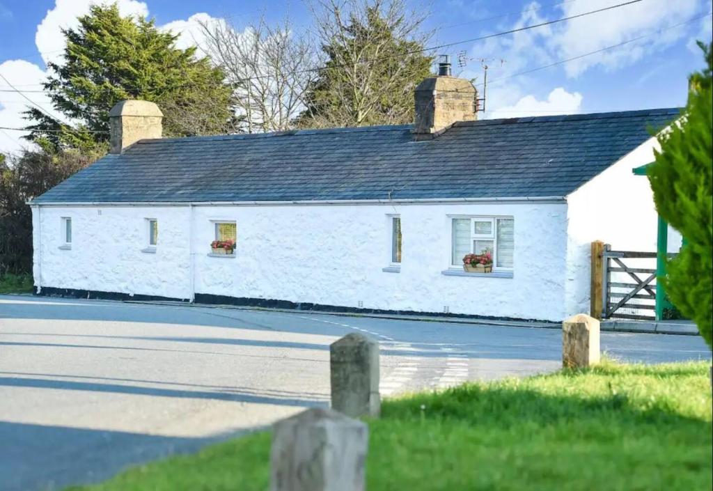 ein weißes Haus mit einem schwarzen Dach auf einer Straße in der Unterkunft Detached cottage near to Abersoch in Abersoch
