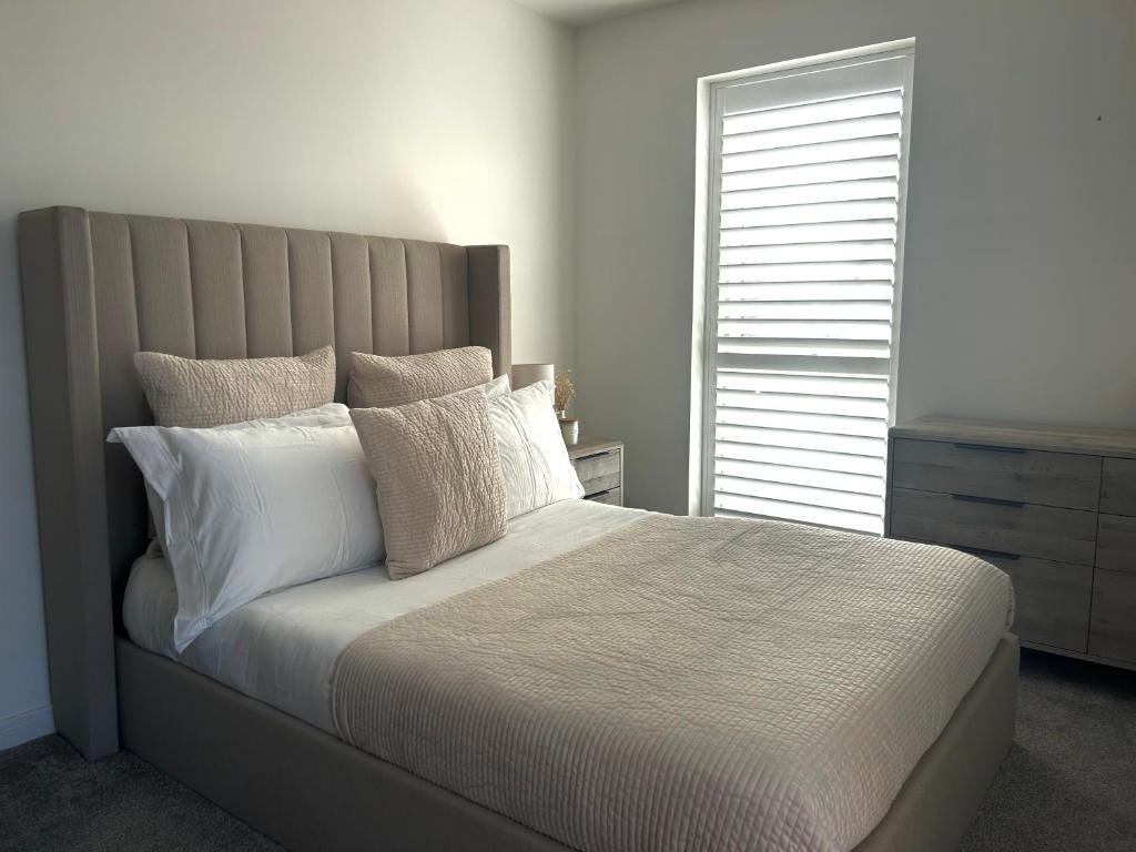 a bedroom with a bed with white pillows and a window at Millicent Room in Littlehampton