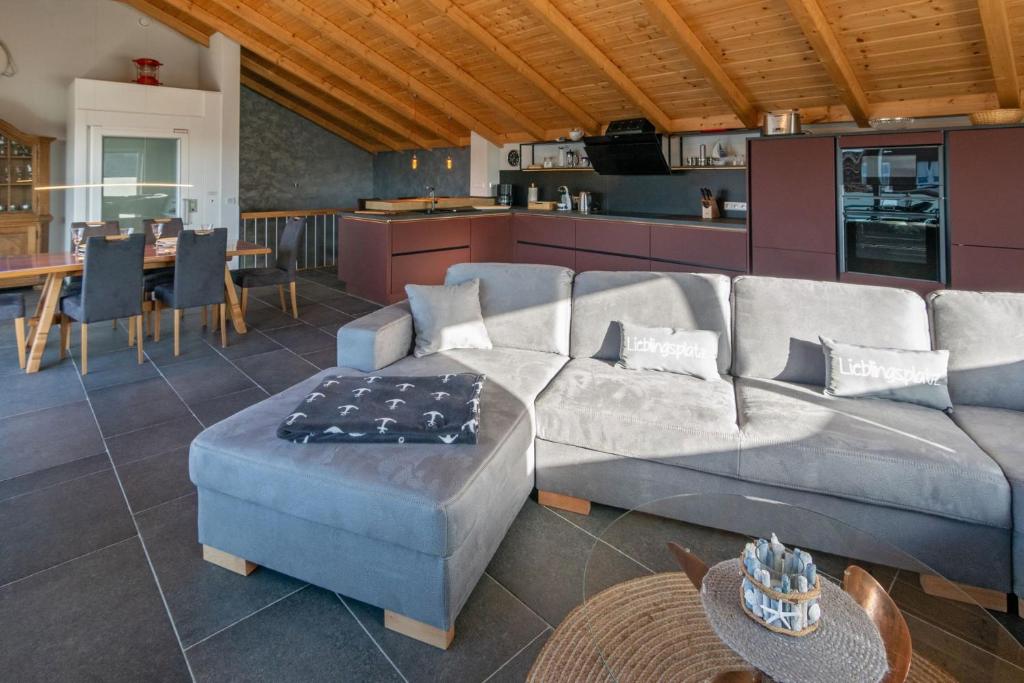 a living room with a large couch and a kitchen at Luxus 5 Sterne Ferienhaus Voslapp in Norden
