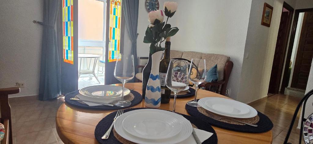 a wooden table with plates and wine glasses on it at Casa de la Felicidad cerca de la playa in Santa Pola