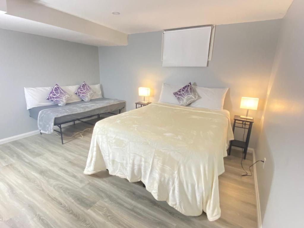 a white room with a bed and a bench at Bancroft VIBES l Sleep 7 l BBQ I FIRE PIT in Bancroft