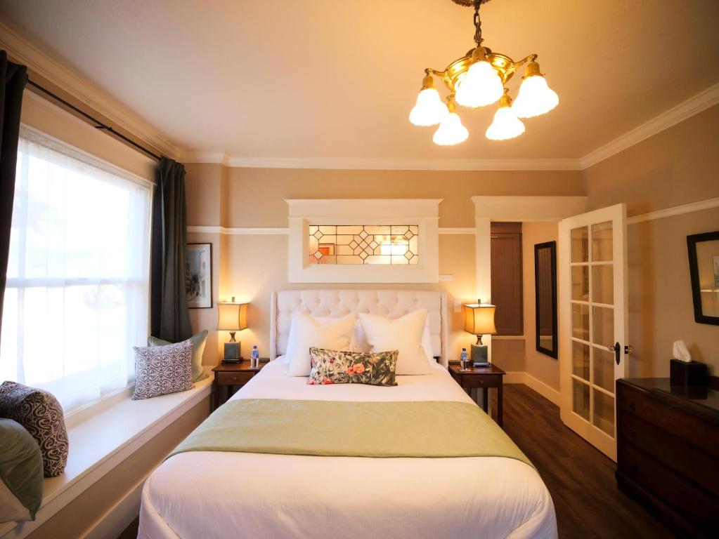 a bedroom with a white bed with a window and a chandelier at RedTail Inn - 3 Suites Sleeps up to 12 in Ashland