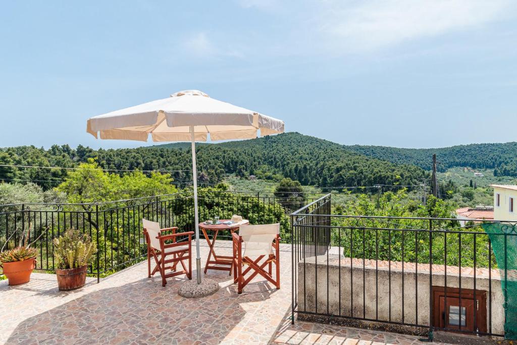 a table and chairs with an umbrella on a balcony at Pefkos Cottage in Panormos Skopelos