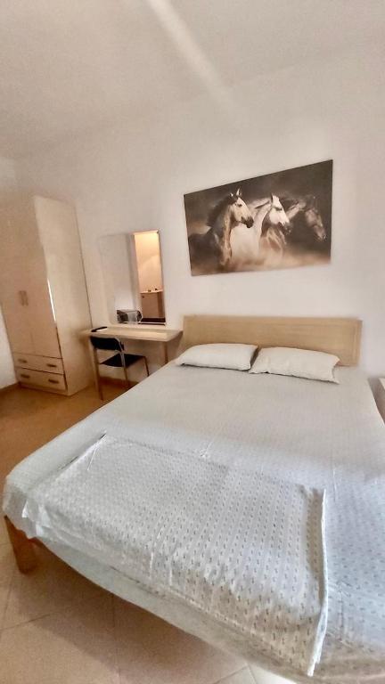 a bedroom with a white bed with a painting on the wall at Mar in Durrës