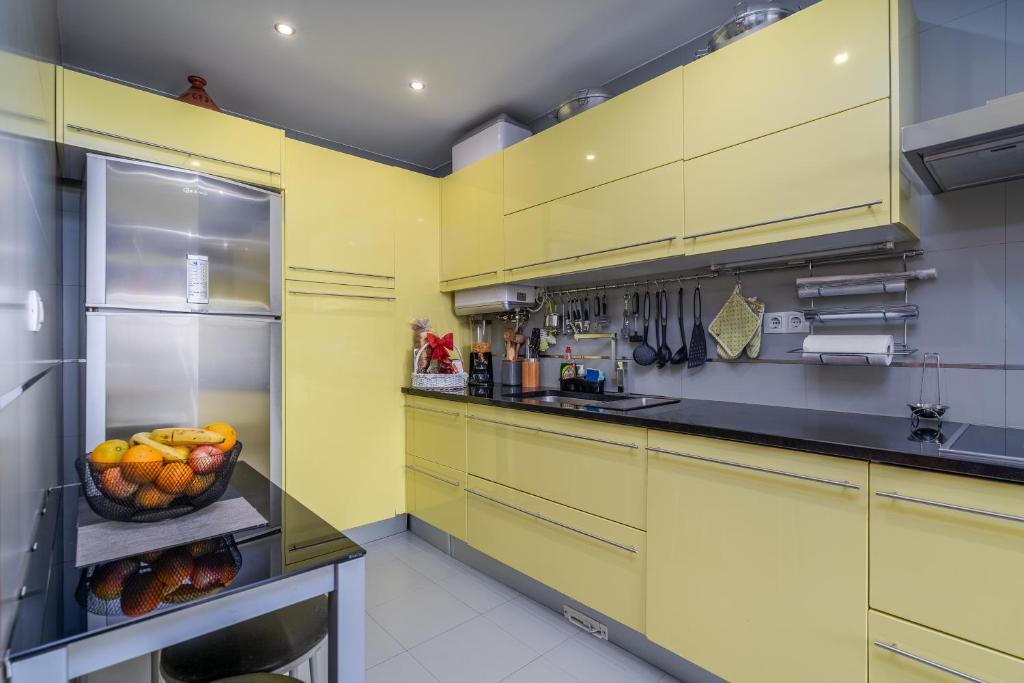 a kitchen with yellow cabinets and a bowl of fruit at Vila Cantinho Algarvio Vista Rio in Ferragudo
