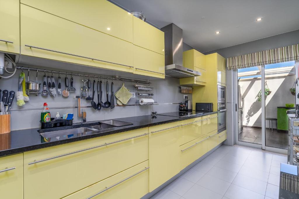 a kitchen with yellow cabinets and utensils on the wall at Vila Cantinho Algarvio Vista Rio in Ferragudo