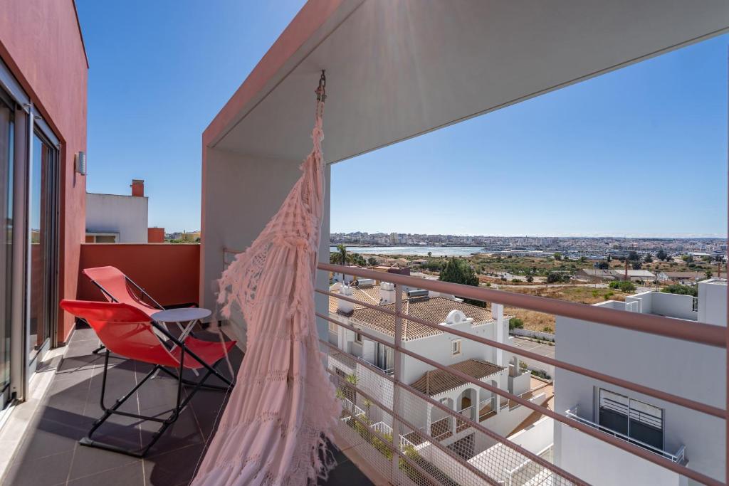 a balcony with a red chair and a hammock at Vila Cantinho Algarvio Vista Rio in Ferragudo