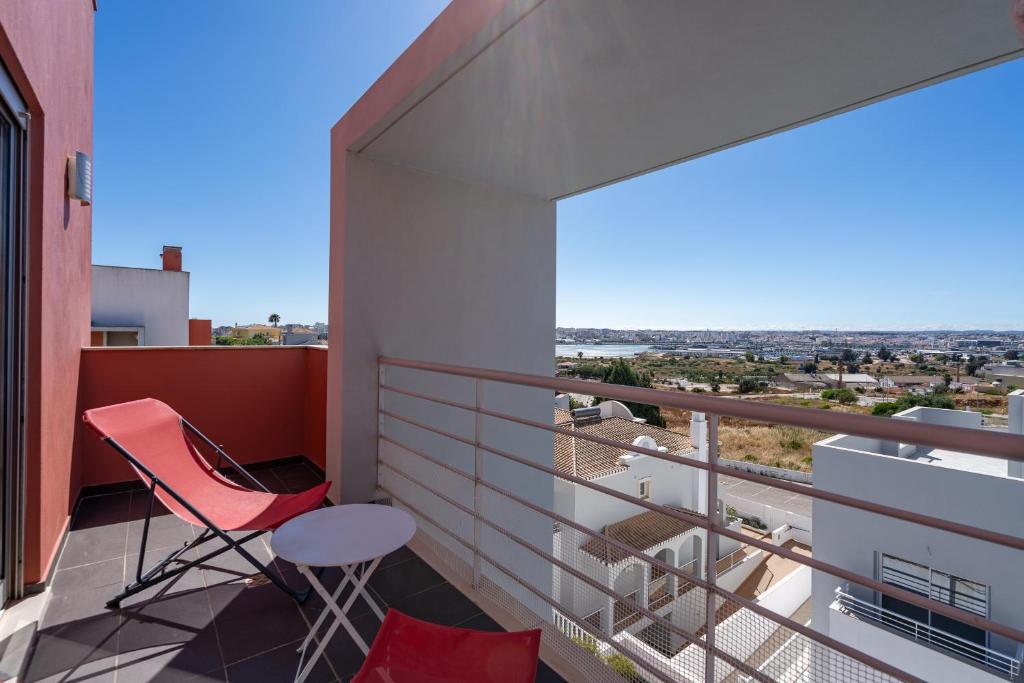 a balcony with a red chair and a view at Vila Cantinho Algarvio Vista Rio in Ferragudo