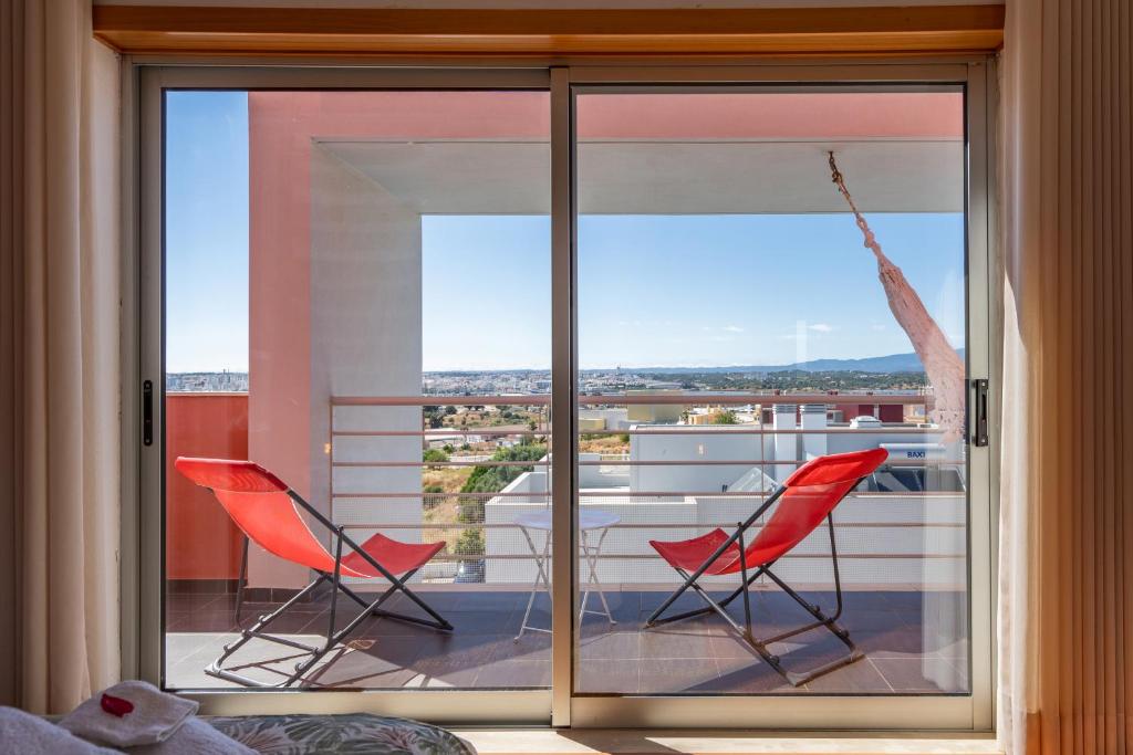 two red chairs sitting on a balcony with a window at Vila Cantinho Algarvio Vista Rio in Ferragudo
