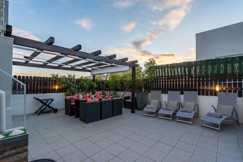 a patio with a table and chairs under a pergola at Vila Cantinho Algarvio Vista Rio in Ferragudo