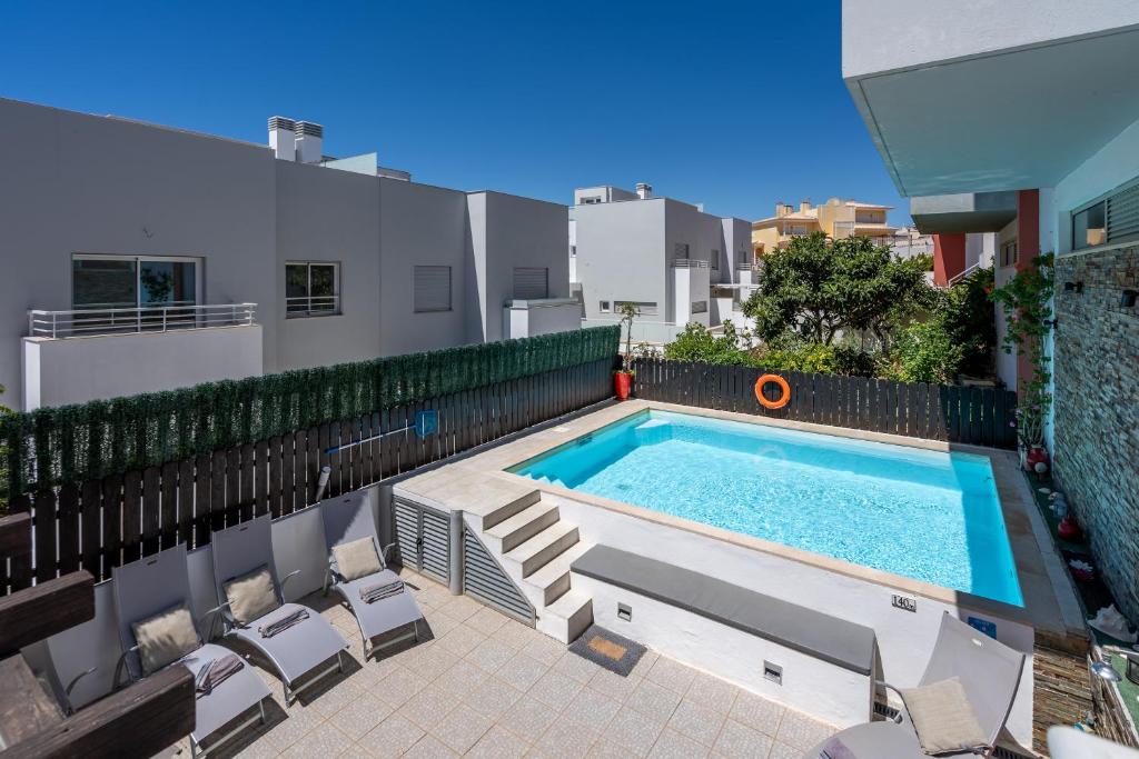 a swimming pool with chairs next to a building at Vila Cantinho Algarvio Vista Rio in Ferragudo